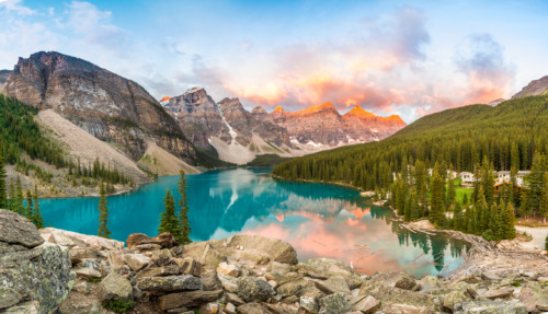 Moraine Lake in de Canadese Rocky Mountains bij zonsopgang, omringd door bergpieken en dichte bossen