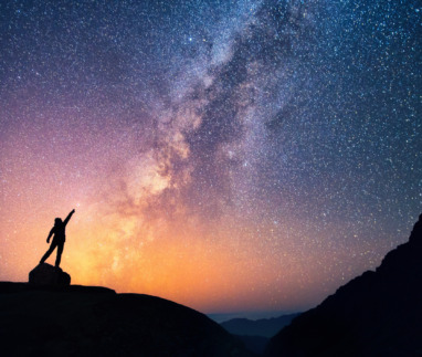 Silhouet van een reiziger onder een fonkelende sterrenhemel met de Melkweg op de achtergrond