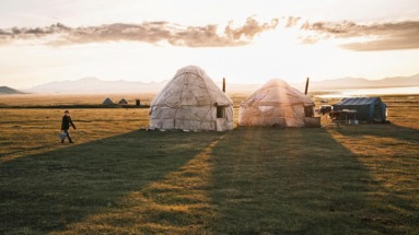 Traditionele yurts in de uitgestrekte graslanden van Kirgizië bij zonsondergang.