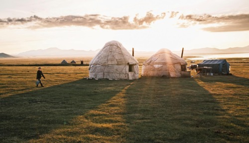 Traditionele yurts in de uitgestrekte graslanden van Kirgizië bij zonsondergang.