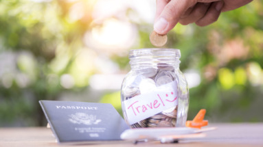 Spaarpot met reisbudget, paspoort en mini-vliegtuig op een tafel