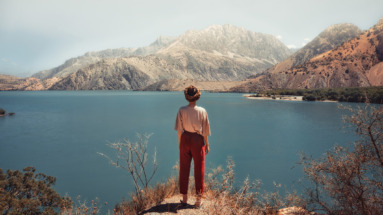 Een reiziger geniet van het uitzicht over het Iskanderkul-meer, omringd door de Fann-gebergte in Tadzjikistan.