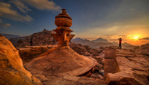 Zonsondergang boven de oude stad Petra in Jordanië, met een fotograaf die het uitzicht vastlegt.