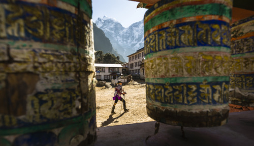 Een trekker loopt langs gebedsmolens bij de Tengboche Monastery met Himalaya-pieken op de achtergrond in Sagarmatha National Park, Nepal.