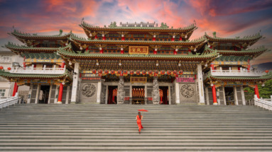 Een vrouw in traditionele kleding loopt de trappen op naar de kleurrijke tempel Sanfeng Gong in Kaohsiung, Taiwan.