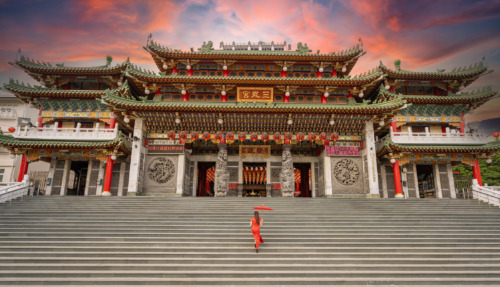 Een vrouw in traditionele kleding loopt de trappen op naar de kleurrijke tempel Sanfeng Gong in Kaohsiung, Taiwan.