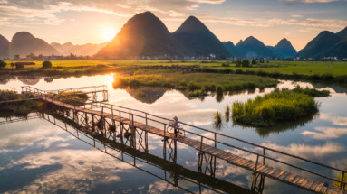 Traditionele brug over een rivier tussen rijstvelden en karstbergen in Bac Son Valley, Lang Son, Vietnam bij zonsopgang.