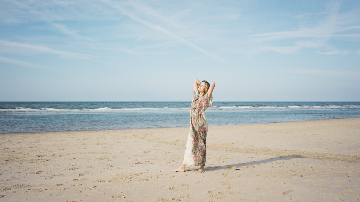 Mature woman stretching on the beach, enjoying the sun