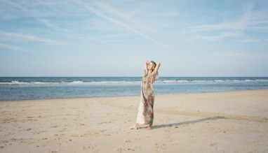 Mature woman stretching on the beach, enjoying the sun