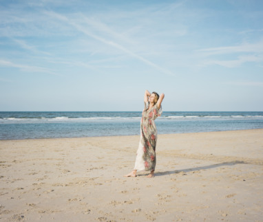 Mature woman stretching on the beach, enjoying the sun