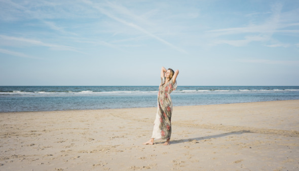 Mature woman stretching on the beach, enjoying the sun