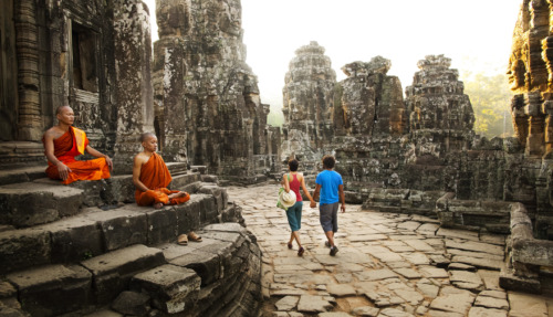 Twee boeddhistische monniken zitten in meditatie bij de oude tempels van Angkor, terwijl een stel hand in hand door de historische ruïnes wandelt.
