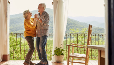 Bejaard koppel danst verliefd en vrolijk op een balkon in de zon