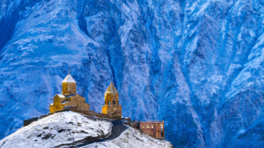 De Gergeti Drievuldigheidskerk tegen een besneeuwd Kaukasusgebergte in Georgië.
