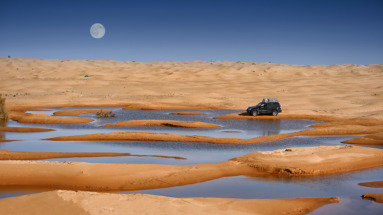 4x4-auto in een woestijnoase onder de volle maan in de Sahara, Tunesië.