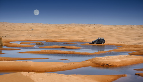 4x4-auto in een woestijnoase onder de volle maan in de Sahara, Tunesië.