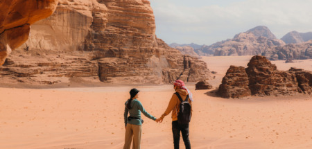 Een reizend koppel geniet van het uitzicht over het adembenemende woestijnlandschap Wadi Rum in Jordanië, het Midden-Oosten.