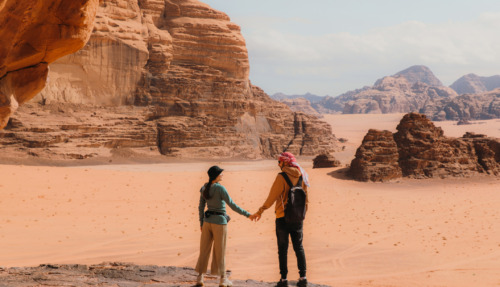 Een reizend koppel geniet van het uitzicht over het adembenemende woestijnlandschap Wadi Rum in Jordanië, het Midden-Oosten.