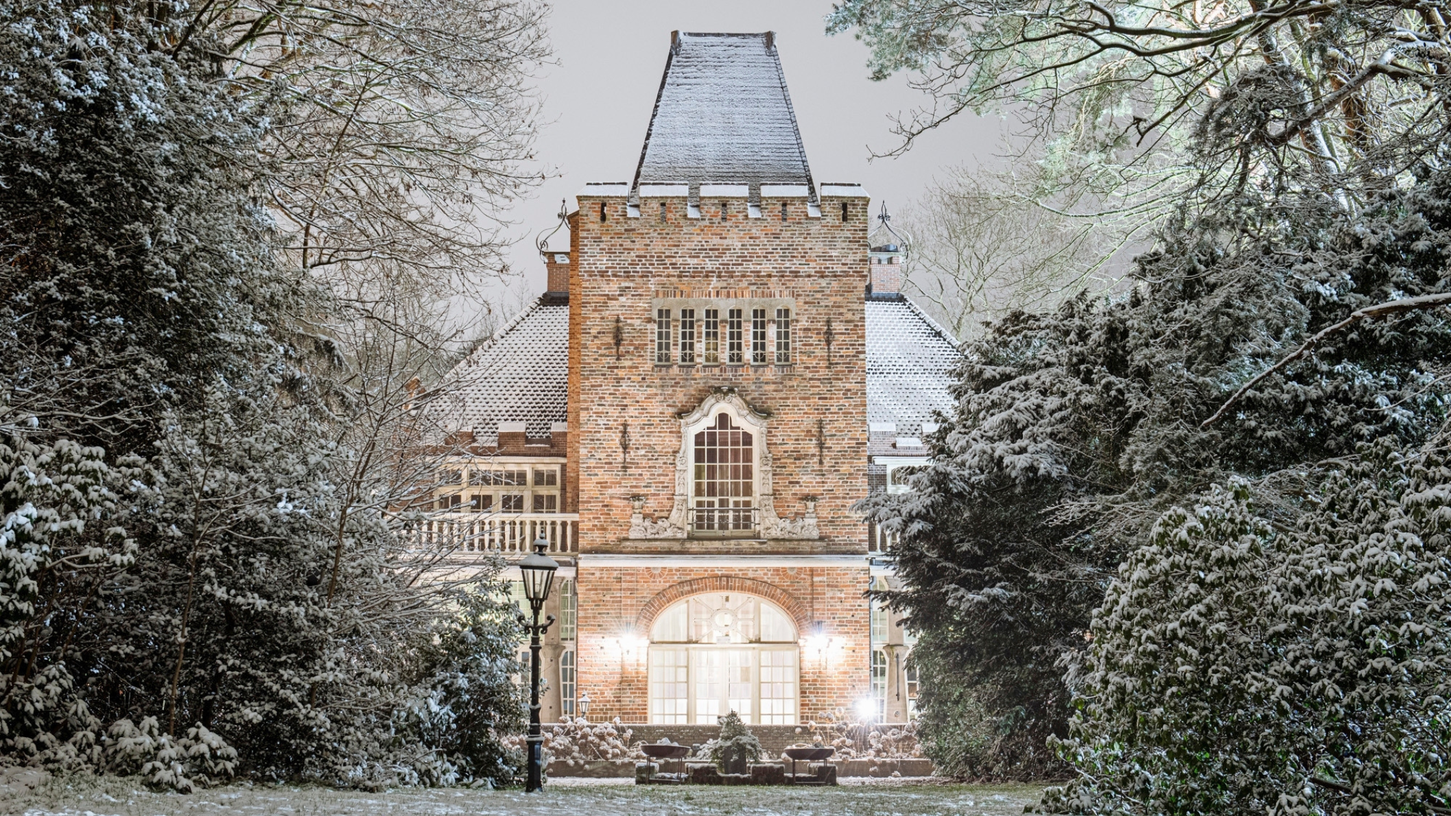 Sprookjesachtig verlicht Kasteel Kerckebosch in Zeist tijdens een winterse avond, omgeven door besneeuwde bomen en een sfeervol verlichte tuin. Foto: Stefan van Dorrestein