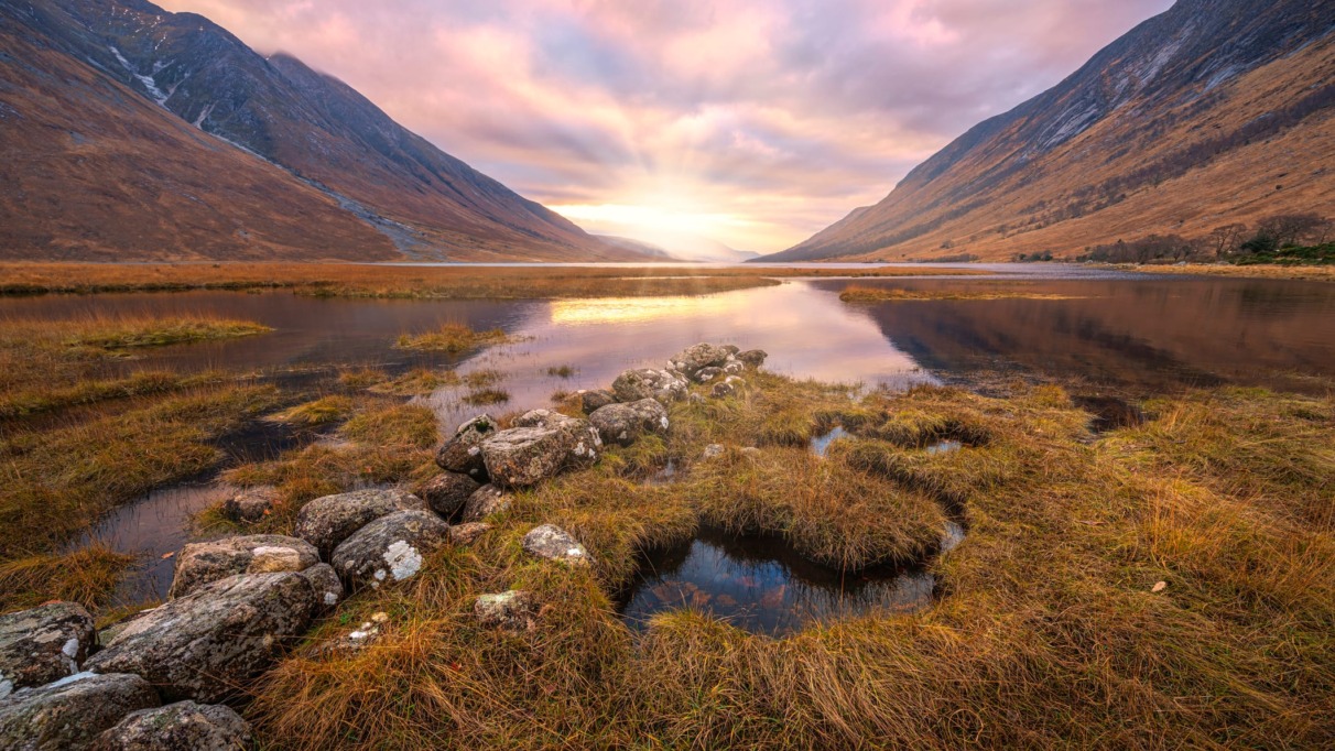 Adembenemend Schots hooglandlandschap bij zonsopgang, met reflecties in het water