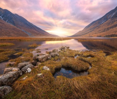 Adembenemend Schots hooglandlandschap bij zonsopgang, met reflecties in het water