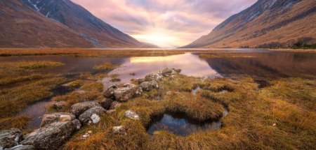 Adembenemend Schots hooglandlandschap bij zonsopgang, met reflecties in het water
