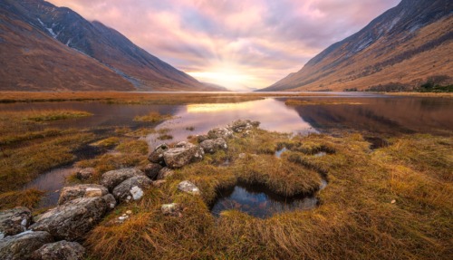 Adembenemend Schots hooglandlandschap bij zonsopgang, met reflecties in het water