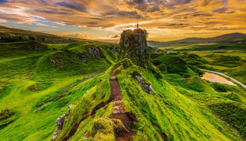 Spectaculair Schots landschap bij zonsondergang, met een wandelaar op een rotspunt van Isle of Skye