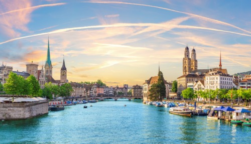 Uitzicht op de rivier de Limmat met de skyline van Zürich bij zonsondergang