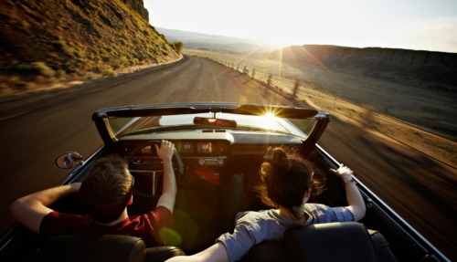 Twee reizigers in een klassieke cabriolet tijdens een roadtrip door de Verenigde Staten bij zonsondergang
