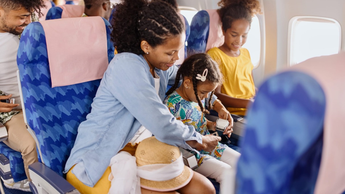 Moeder maakt de veiligheidsriem vast van haar dochter tijdens een vlucht