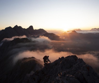 Bergsporter klimt bij zonsopkomst door de Alpen in Tirol