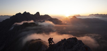 Bergsporter klimt bij zonsopkomst door de Alpen in Tirol