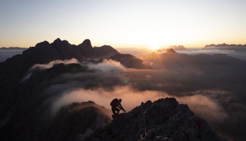 Bergsporter klimt bij zonsopkomst door de Alpen in Tirol