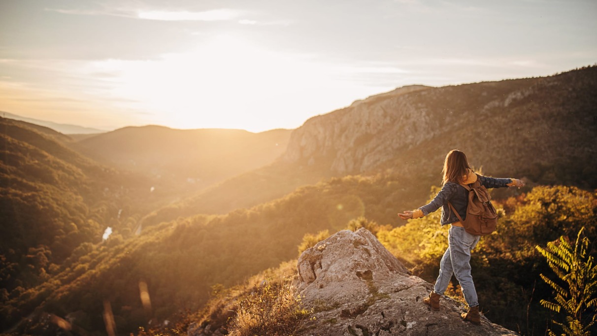 Jonge vrouw met rugzak gelukkig op de top van een berg