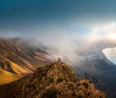 Stel staat bovenop een klif om naar de zonsondergang te kijken op Lanzarote, Canarische eilanden