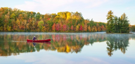 Oudere man kanoot over meer in Minnesota in de herfst