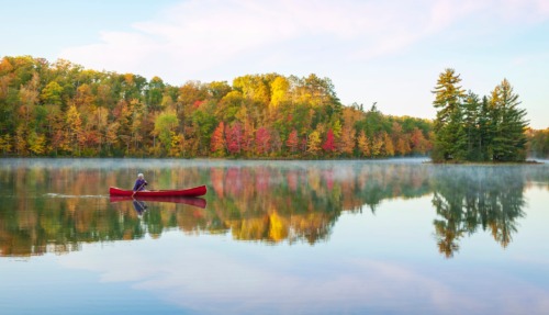 Oudere man kanoot over meer in Minnesota in de herfst
