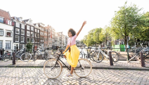 Vrouw fietst vrolijk door Amsterdam
