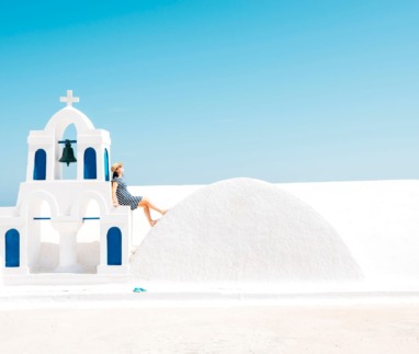 Vrouw leunt op kapelletje in Oia, Santorini, Griekenland