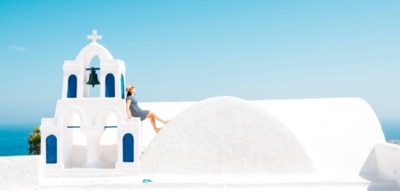 Vrouw leunt op kapelletje in Oia, Santorini, Griekenland