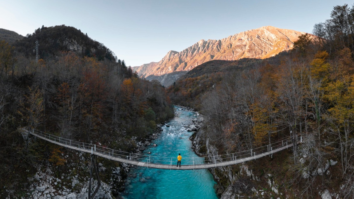 Man standing on a suspension bridge above a mountain river