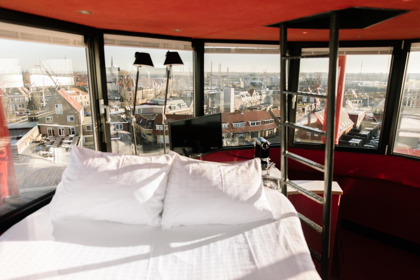 Luxe bed met panoramisch uitzicht over de daken en haven van Harlingen vanuit een omgebouwde vuurtoren.