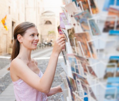 Vrouwelijke toerist kiest een ansichtkaart uit op Sardinië, Italië