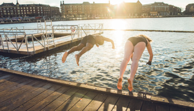Twee vrienden van verschillende leeftijd en afkomst die in Kopenhagen, Denemarken in koud water springen