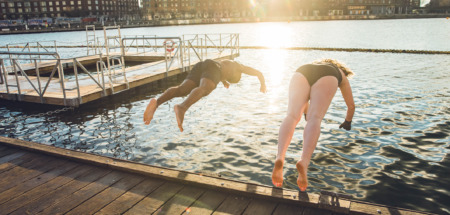 Twee vrienden van verschillende leeftijd en afkomst die in Kopenhagen, Denemarken in koud water springen