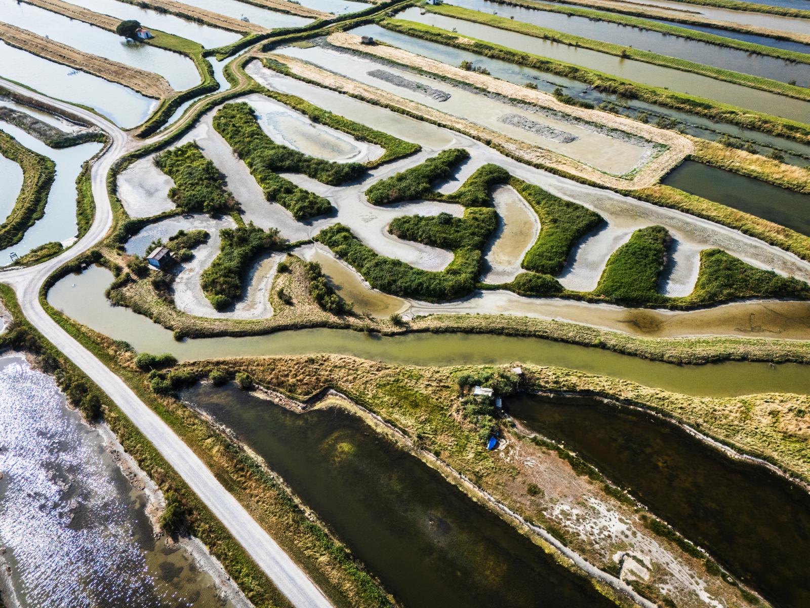 Luchtfoto van kronkelende waterwegen, lagunes en zoutpannen in de Vendée, omringd door groene eilanden en smalle zandbanken