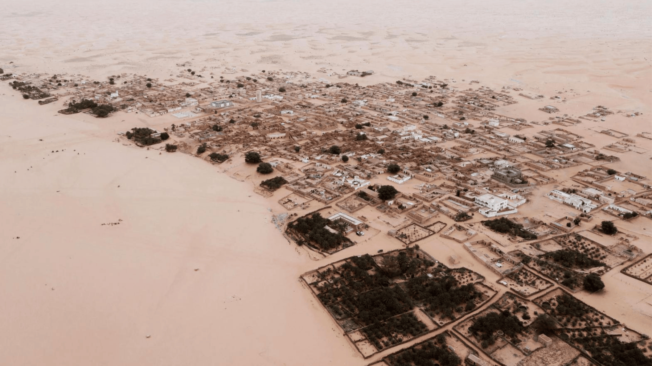 Luchtfoto van Chinguetti, een woestijnstad in Mauritanië, omringd door zandduinen.