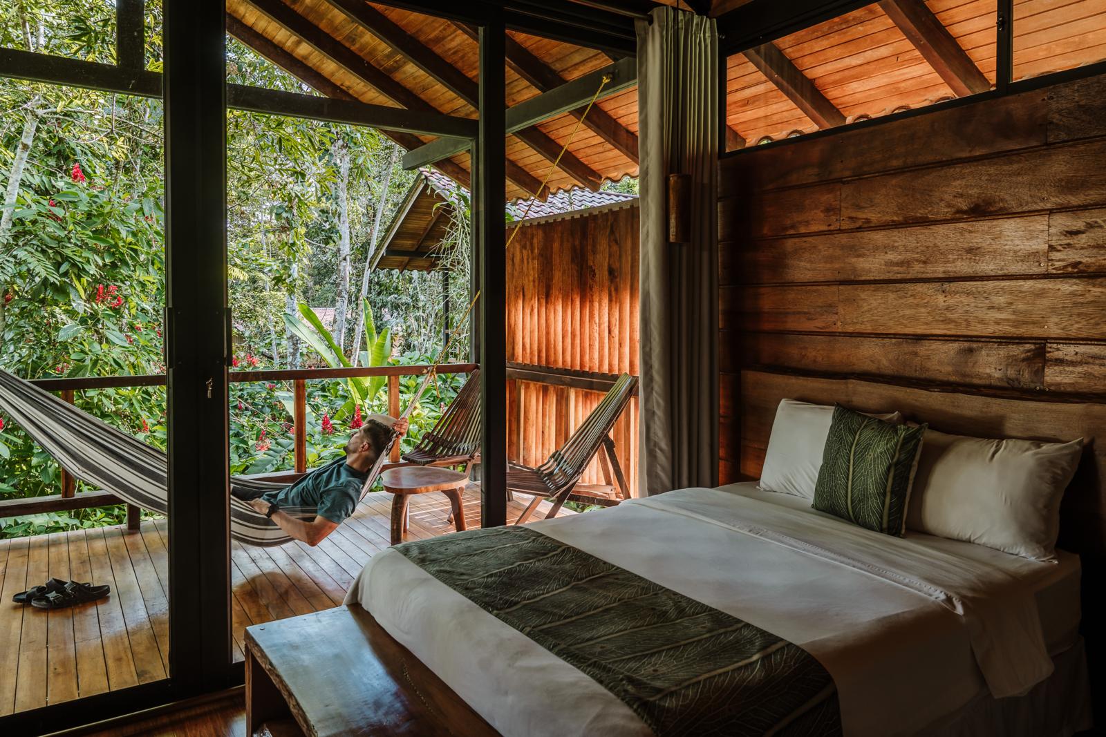 Man ontspant in een hangmat op het balkon van een houten ecolodge in de jungle van Ecuador.