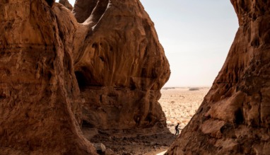 Man wandelt tussen imposante rode rotsformaties in de Adrar-woestijn van Mauritanië.